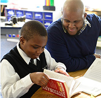 A student wearing the Titusville Academy school uniform working with a teacher in class