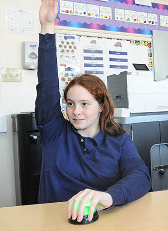 female TTA student at desk raising hand to answer a question
